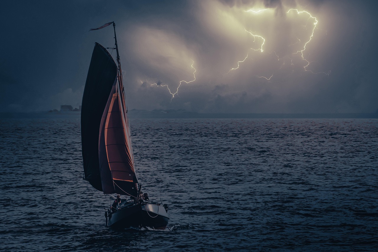 sailboat in front of storm clouds with lightning
