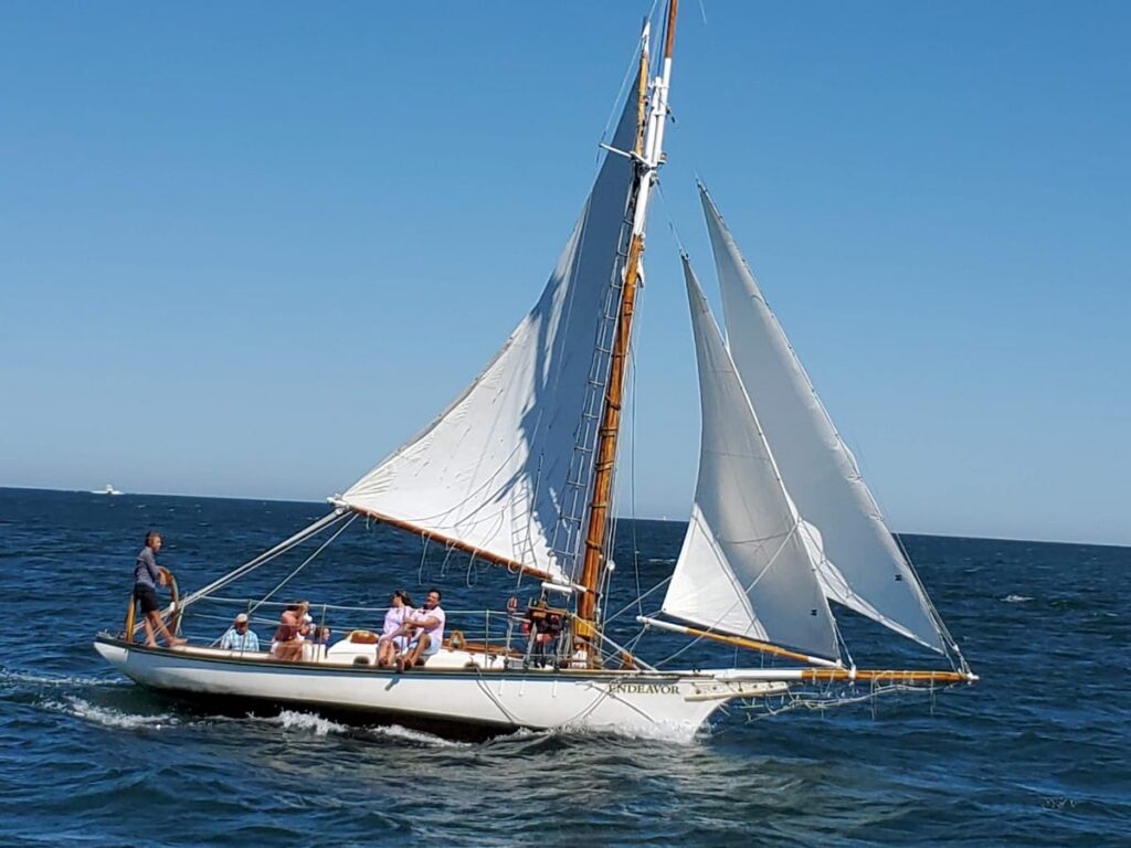 cutter sailboat example in water with three sails extended one large to left from main mast and two smaller to right from main mast