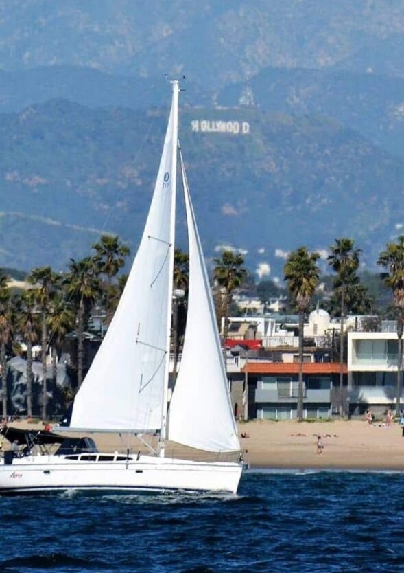 sloop sailboat example in water with both sails extended in front of shoreline